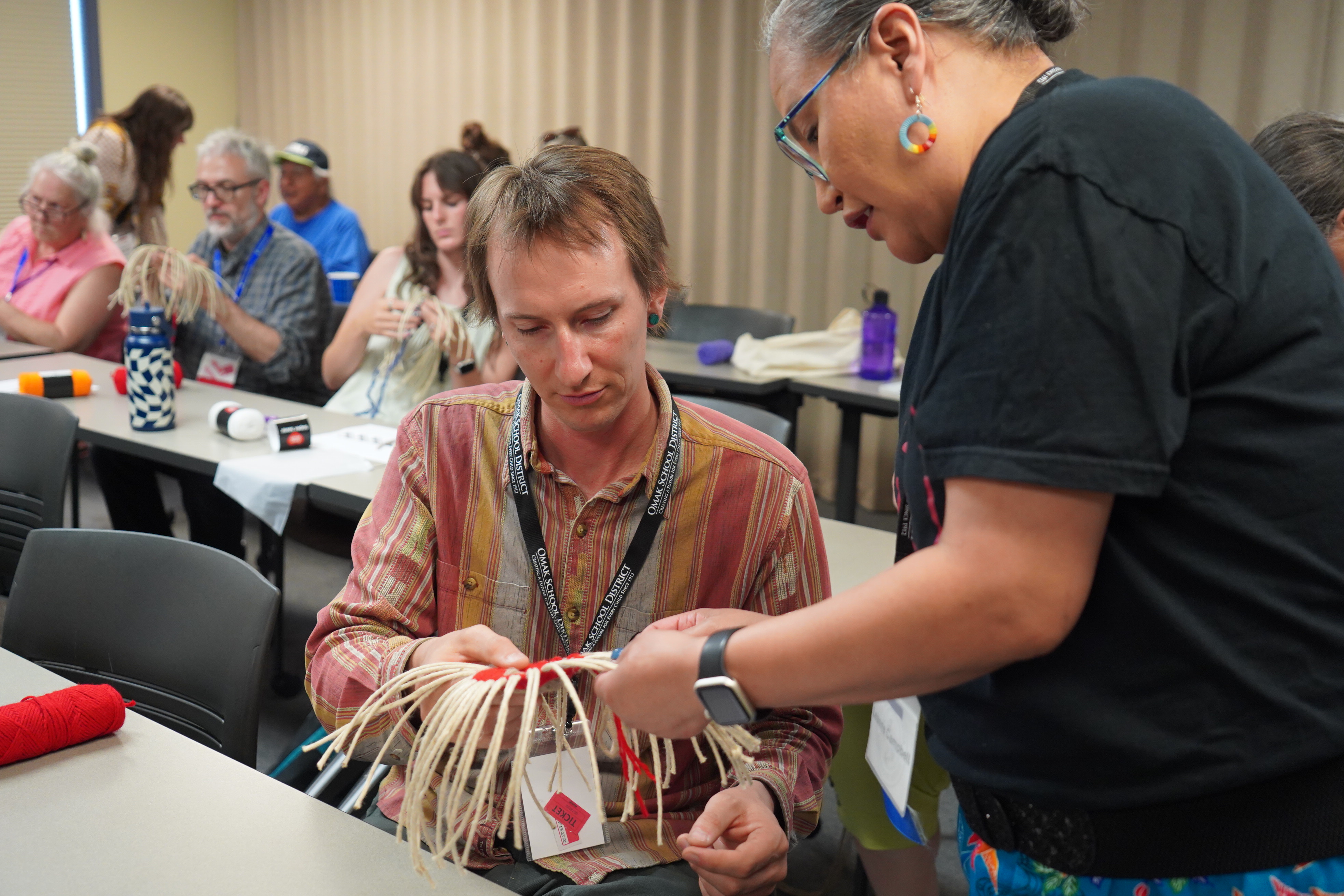 Photograph of WVC faculty member Saxon Spillman being instructed on weaving by Leanne Campbell, Colville Tribes Language Program Manager