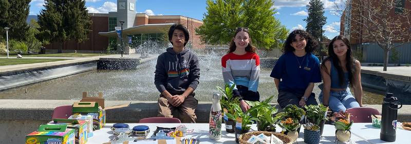 Three students at table with plants.