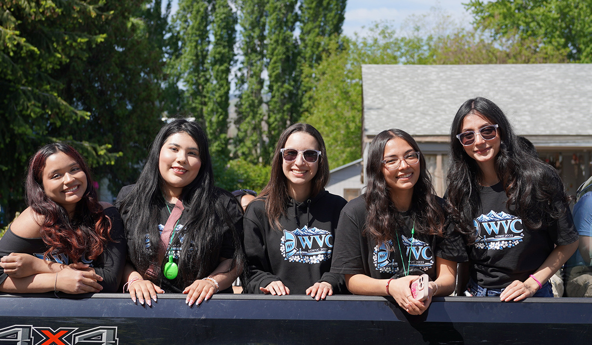 Several WVC senate members wearing sunglasses sit in the back of a pickup and smile at the camera.