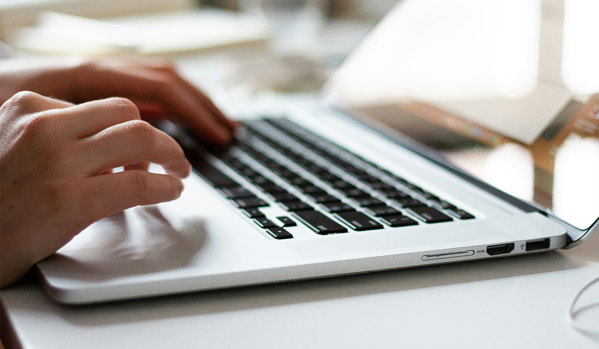 A pair of hands type on a laptop keyboard.