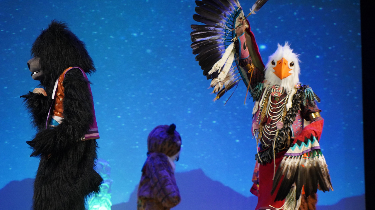 Native dancers are dressed as an eagle, a bear, and a mountain lion.