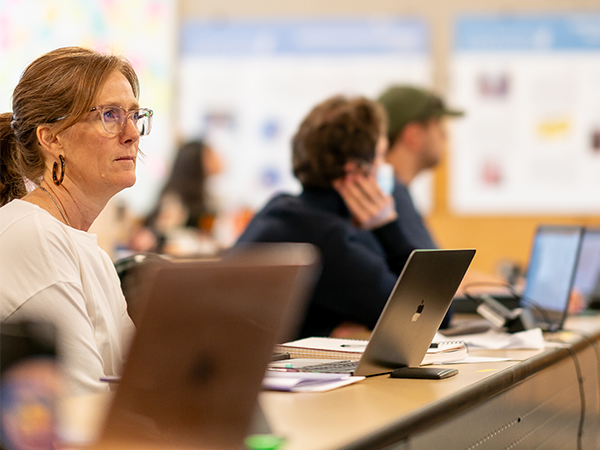 A nursing student sits at a table with her laptop open