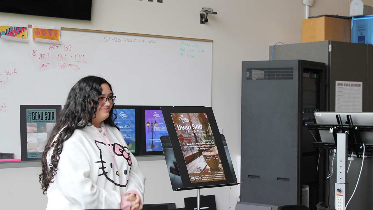 A graphic design student presents her poster project to a group of people.