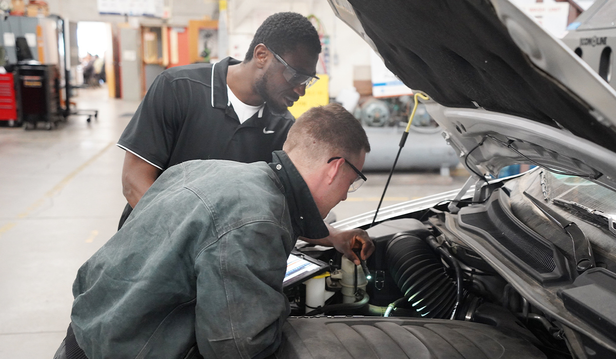 Two WVC auto tech students investigate a car's engine.
