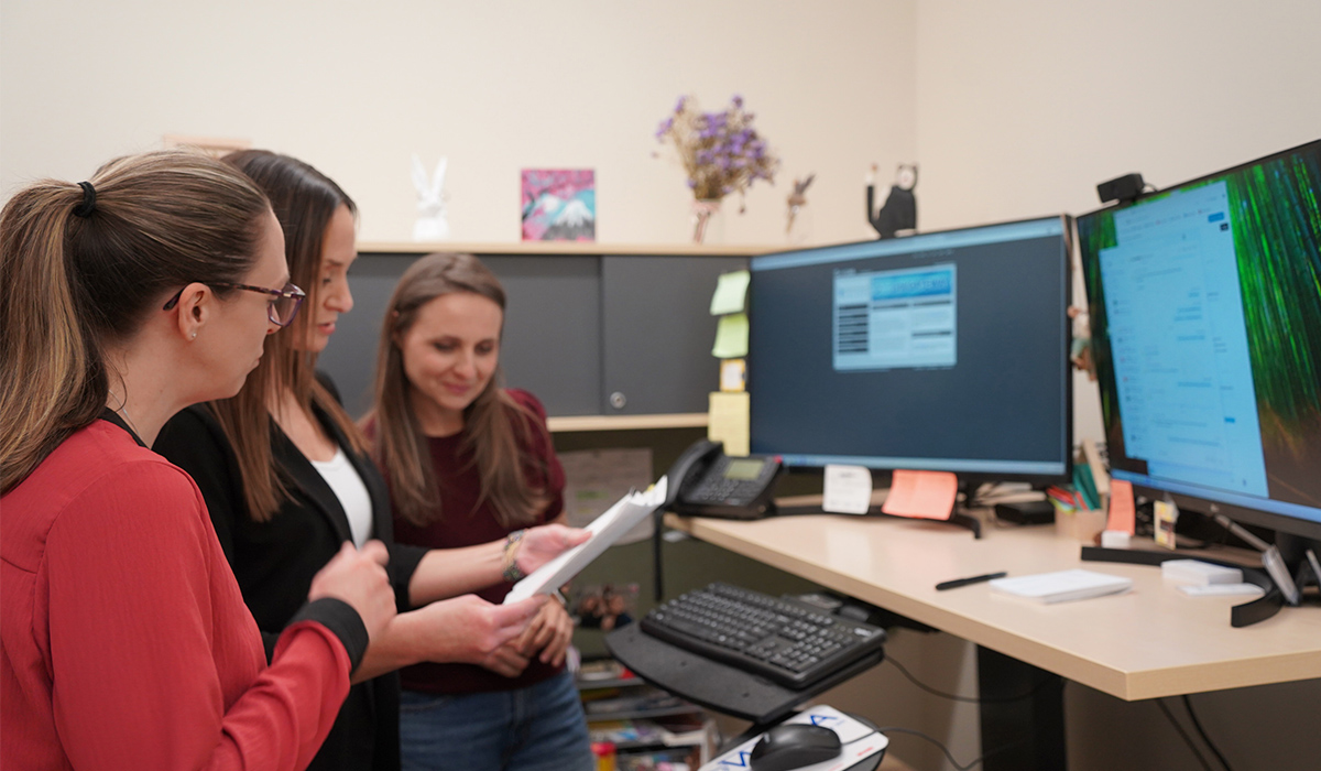 Three staff members review a document together.