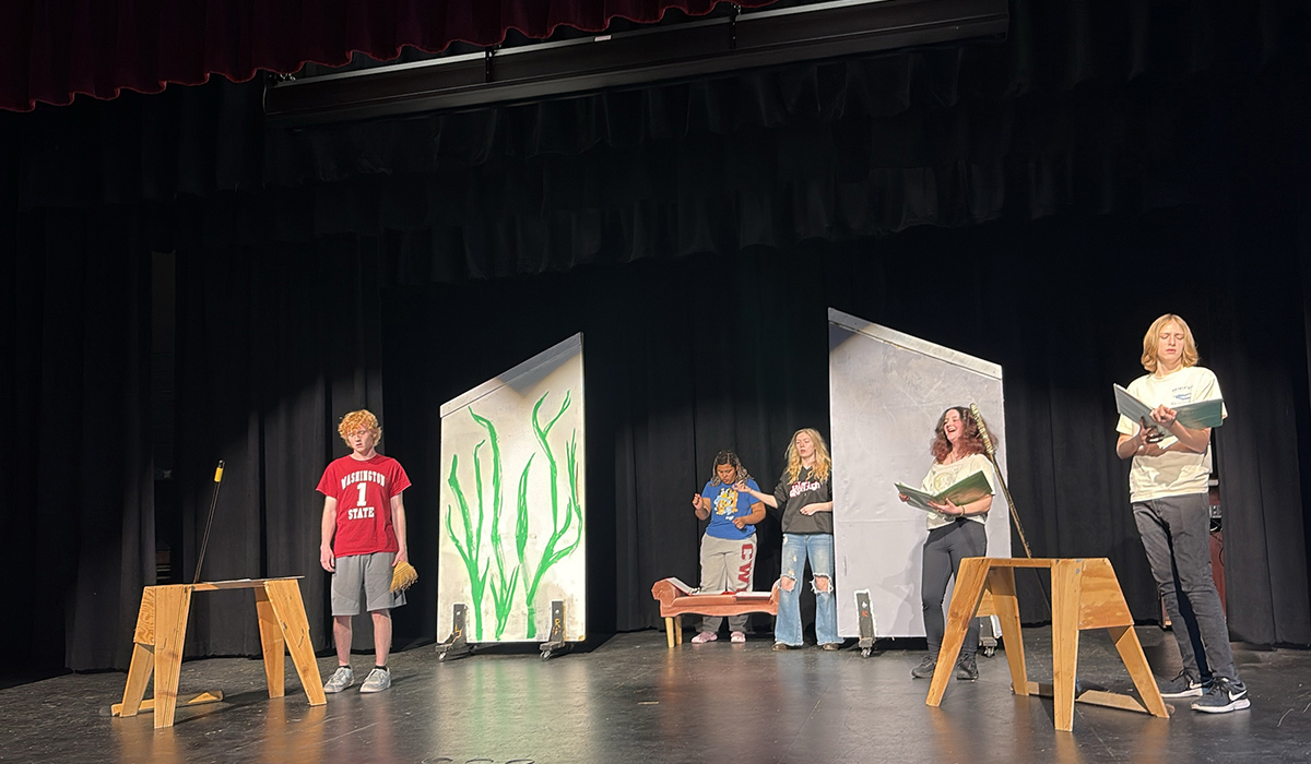 Students practice a play on stage.