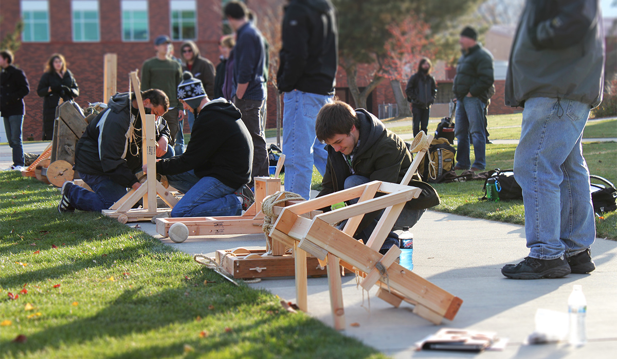 Physics students work on small wood catapult launches.