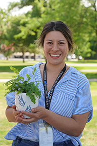Portrait of Kristen Baltz standing outside holding a potted plant