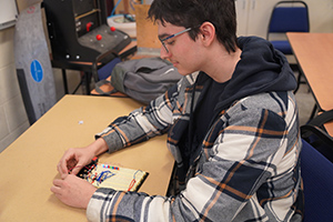 WVC student Logan Swank sits at a desk and works on an electronics project.
