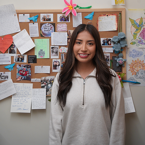Magali Olguin portrait in front of bulletin board.