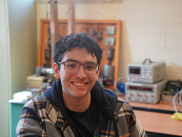 Portrait of WVC Industrial Technology student Logan Swank sitting among electronics equipment.