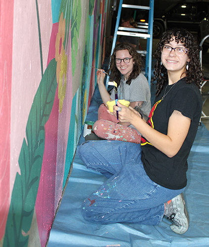 Ellen Bruex with students who created a mural in a parking area.
