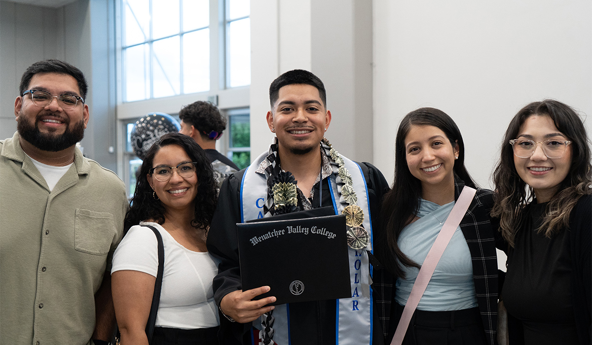 A CAMP graduate stands with several CAMP staff members and holds up his diploma