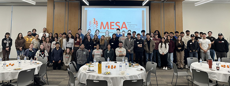 A group of MESA students standing against a presentation screen